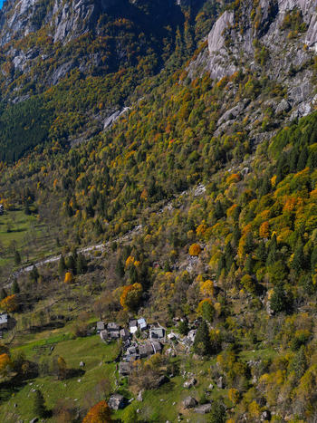 Aerial view of Val di Mello with autumn forest colors on steep rocky slopes and a small stone village in Val Masino Lombardia Italy. Aerial view of Val di Mello with autumn forest colors on steep rocky slopes and a small stone village in Val Masino Lombardia Italy.