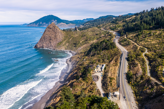 Aerial view of highway 101 construction along the rugged Oregon coastline with cliffs forest and ocean waves in Port Orford Oregon United States. Aerial view of highway 101 construction along the rugged Oregon coastline with cliffs forest and ocean waves in Port Orford Oregon United States.