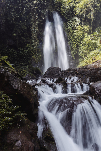 View of Grojogan Sewu Loket 2 waterfall cascading down a lush green cliff into a rocky stream with flowing water Kecamatan Tawangmangu Jawa Tengah Indonesia.