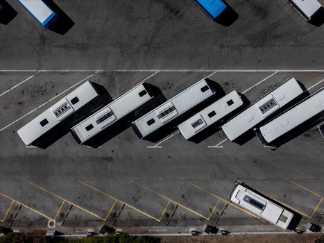 Aerial view of white buses parked in a diagonal formation in a paved lot in Evora Evora District Portugal. Aerial view of white buses parked in a diagonal formation in a paved lot in Evora Evora District Portugal.