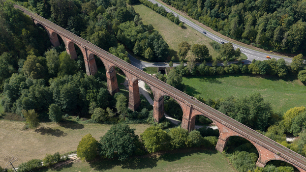 Aerial view of the historic Himbaechel Viaduct a red brick railway bridge spanning a lush green valley surrounded by dense forests and rural landscapes in Erbach Hessen Germany.