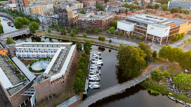 Aerial view of a canal with docked boats a modern building complex and a pedestrian bridge in the city of Zwolle Overijssel Netherlands at sunset.
