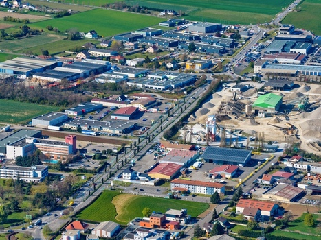 Aerial view of industrial and commercial buildings interspersed with green fields a vibrant tapestry of urban and rural life Sausheim Grand Est France.