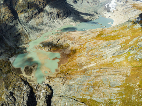 Aerial view of the Grossglockner High Alpine Road and the turquoise glacial lake surrounded by rugged mountain peaks and rocky slopes in Zell am See District Salzburg Austria.
