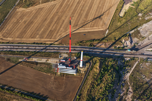 Aerial view of the construction of a wind turbine at the lignite open cast mine Schleenhain with a large crane turbine blades and surrounding agricultural fields in Zwenkau Saxony Germany.