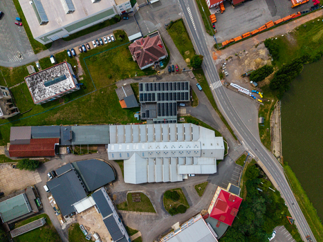 Aerial view of an industrial facility with metal roofed warehouses solar panels and parking areas near a road and water in Zebrak Central Bohemian Region Czechia. Aerial view of an industrial facility with metal roofed warehouses solar panels and parking areas near a road and water in Zebrak Central Bohemian Region Czechia.