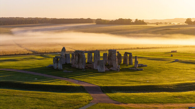 Aerial view of Stonehenge surrounded by lush green fields and morning mist at sunrise in Salisbury England United Kingdom. Aerial view of Stonehenge surrounded by lush green fields and morning mist at sunrise in Salisbury England United Kingdom.