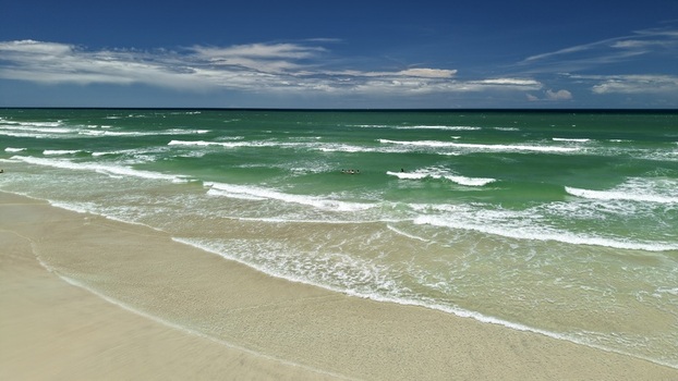 Aerial view of Matanzas Inlet featuring turquoise ocean waves rolling onto a sandy beach with people swimming in the clear water in St. Johns County Florida United States. Aerial view of Matanzas Inlet featuring turquoise ocean waves rolling onto a sandy beach with people swimming in the clear water in St. Johns County Florida United States.