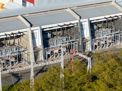Aerial view of an electrical substation featuring high voltage transformers power lines and industrial infrastructure surrounded by green trees Slovenia.