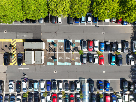 Aerial view of a parking lot with rows of cars and electric vehicle charging stations next to green trees in Turin Piedmont Italy. Aerial view of a parking lot with rows of cars and electric vehicle charging stations next to green trees in Turin Piedmont Italy.