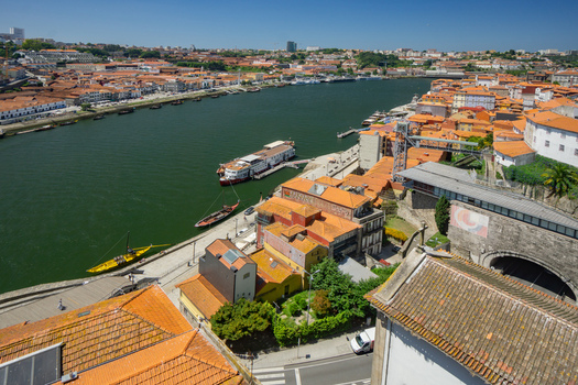 Aerial view of the Douro River snaking through Porto lined with buildings boasting terracotta roofs creating a vibrant contrast against the deep green waters Porto Porto District Portugal. Aerial view of the Douro River snaking through Porto lined with buildings boasting terracotta roofs creating a vibrant contrast against the deep green waters Porto Porto District Portugal.