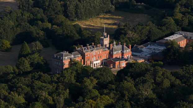 Aerial view of The Ridings at Theobalds Estate a historic red brick mansion surrounded by dense woodland and green parkland in Cheshunt England United Kingdom.