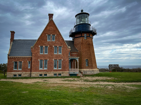 View of the historic Block Island Southeast Light with its red brick facade and tower set against a cloudy sky in New Shoreham Rhode Island United States.
