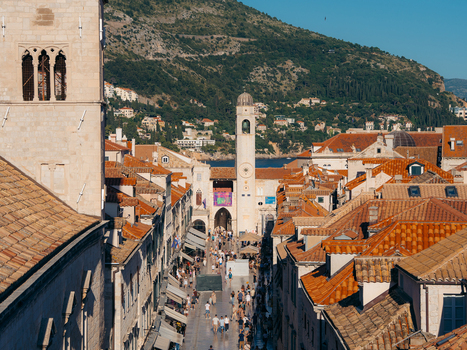 View of Stradun street with people walking between historic buildings and terracotta rooftops in Dubrovnik Dubrovnik Neretva County Croatia. View of Stradun street with people walking between historic buildings and terracotta rooftops in Dubrovnik Dubrovnik Neretva County Croatia.