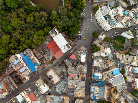 Aerial view of the dense urban landscape of Udaipur featuring a mix of buildings narrow streets and lush green trees bordering the city in Udaipur Rajasthan India.