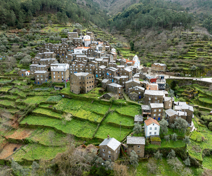 Aerial view of the village nestled in the valley with stone houses and terraced fields a contrast of rustic charm against the verdant landscape Piódão Arganil Portugal. Aerial view of the village nestled in the valley with stone houses and terraced fields a contrast of rustic charm against the verdant landscape Piódão Arganil Portugal.