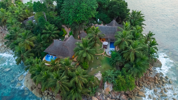 Axim Ghana 09 February 2023 Aerial view of Lou Moon Resort Eco Luxury nestled among lush palm trees and rocky coastline with turquoise ocean waves crashing against the shore. Axim Ghana 09 February 2023 Aerial view of Lou Moon Resort Eco Luxury nestled among lush palm trees and rocky coastline with turquoise ocean waves crashing against the shore.