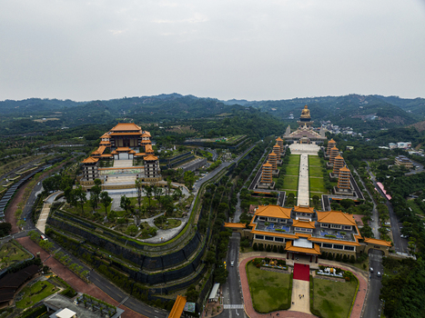 Aerial view of Fo Guang Shan Buddha Museum with grand pagodas expansive walkways and traditional architecture set against lush green hills in Jiuru Township Pingtung County Taiwan. Aerial view of Fo Guang Shan Buddha Museum with grand pagodas expansive walkways and traditional architecture set against lush green hills in Jiuru Township Pingtung County Taiwan.