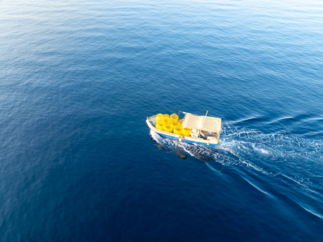 Aerial view of a fishing boat slicing through the deep blue sea its yellow cargo containers a vibrant contrast against the water Ghajnsielem Gozo Malta. Aerial view of a fishing boat slicing through the deep blue sea its yellow cargo containers a vibrant contrast against the water Ghajnsielem Gozo Malta.
