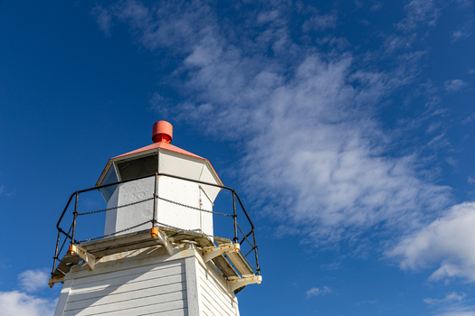 View of the upper section of Laukvik fyr lighthouse with its white wooden structure and red lantern room under a bright blue sky Laukvik Nordland Norway. View of the upper section of Laukvik fyr lighthouse with its white wooden structure and red lantern room under a bright blue sky Laukvik Nordland Norway.