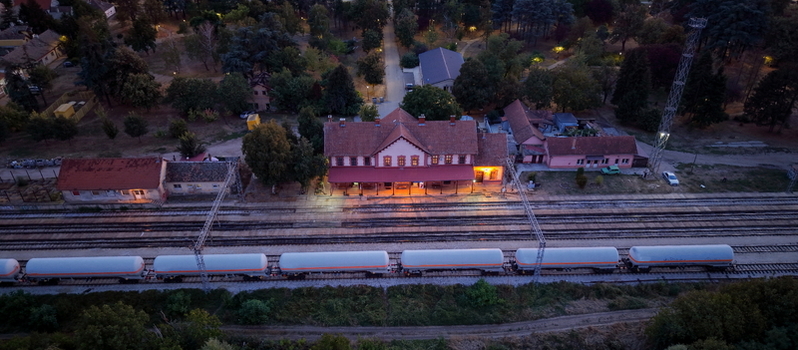 Aerial view of the railway station in Pancevo with a freight train carrying tanker cars on the tracks surrounded by trees and illuminated by warm evening light in Pancevo Serbia. Aerial view of the railway station in Pancevo with a freight train carrying tanker cars on the tracks surrounded by trees and illuminated by warm evening light in Pancevo Serbia.