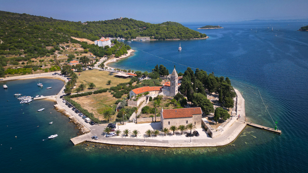Aerial view of the Franciscan Monastery of St. Jerome on Prirovo peninsula with its stone bell tower and red roofs surrounded by turquoise sea in Vis Split Dalmatia County Croatia. Aerial view of the Franciscan Monastery of St. Jerome on Prirovo peninsula with its stone bell tower and red roofs surrounded by turquoise sea in Vis Split Dalmatia County Croatia.