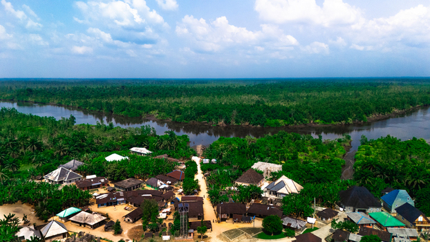 Aerial view of a rural village nestled among lush green forests and palm trees situated along the banks of a winding river in Abua Rivers Nigeria. Aerial view of a rural village nestled among lush green forests and palm trees situated along the banks of a winding river in Abua Rivers Nigeria.