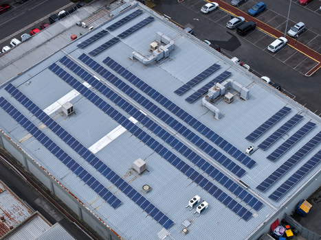 Melbourne VIC Australia 25 September 2026 Aerial view of a large industrial building roof covered with numerous solar panels and HVAC units with a parking lot visible nearby.