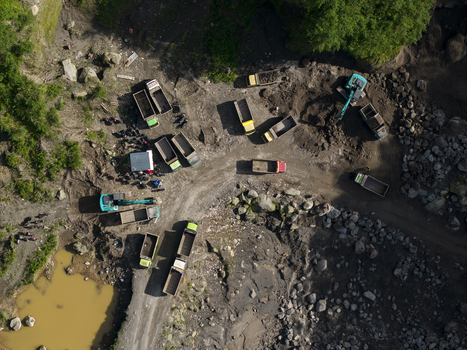 Aerial view of Tambang Pasir Merapi Kali Gendol Sand Mine with trucks and excavators operating on the rocky terrain Kecamatan Cangkringan Daerah Istimewa Yogya Indonesia. Aerial view of Tambang Pasir Merapi Kali Gendol Sand Mine with trucks and excavators operating on the rocky terrain Kecamatan Cangkringan Daerah Istimewa Yogya Indonesia.