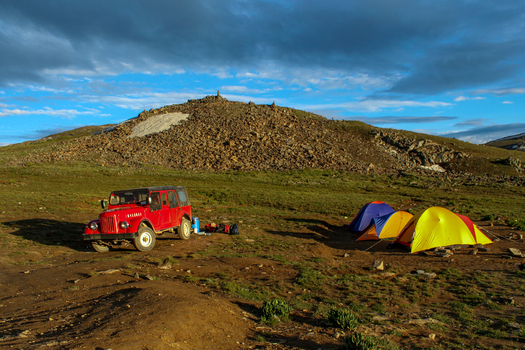 View of a red off road vehicle parked near colorful camping tents on a rocky high altitude landscape near Sheosar Lake in Skardu Pakistan. View of a red off road vehicle parked near colorful camping tents on a rocky high altitude landscape near Sheosar Lake in Skardu Pakistan.