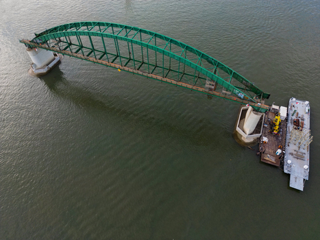 Aerial view of the green arched Savski most bridge spanning the Sava river with a construction barge moored alongside in Belgrade City of Belgrade Serbia. Aerial view of the green arched Savski most bridge spanning the Sava river with a construction barge moored alongside in Belgrade City of Belgrade Serbia.