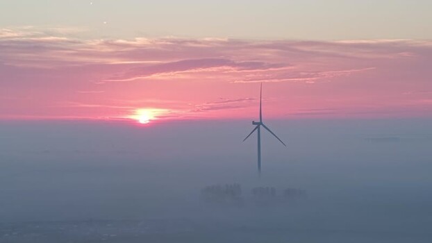 Aerial view of a wind turbine in thick fog at sunset Netherlands. Aerial view of a wind turbine in thick fog at sunset Netherlands.