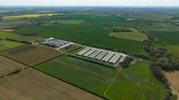 Aerial view of large agricultural farm buildings and industrial sheds surrounded by lush green fields and hedgerows in the rural landscape of Kettering England United Kingdom. Aerial view of large agricultural farm buildings and industrial sheds surrounded by lush green fields and hedgerows in the rural landscape of Kettering England United Kingdom.