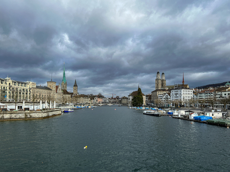 View of the Limmat river in Zurich featuring the historic Grossmunster and Fraumunster churches under a cloudy sky in Zurich Zurich Switzerland.