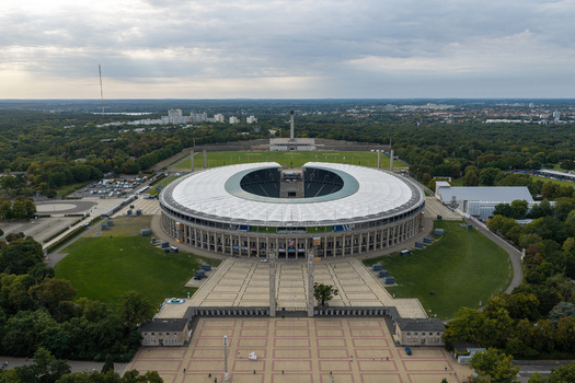 Berlin Germany 26 September 2026 Aerial view of Olympiastadion Berlin surrounded by lush parkland and historic architecture under an overcast sky.