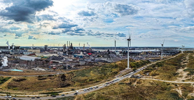 Aerial view of the Tata Steel industrial complex featuring large smokestacks wind turbines and surrounding dunes under a cloudy sky in Velsen Noord Noord Holland Netherlands. Aerial view of the Tata Steel industrial complex featuring large smokestacks wind turbines and surrounding dunes under a cloudy sky in Velsen Noord Noord Holland Netherlands.