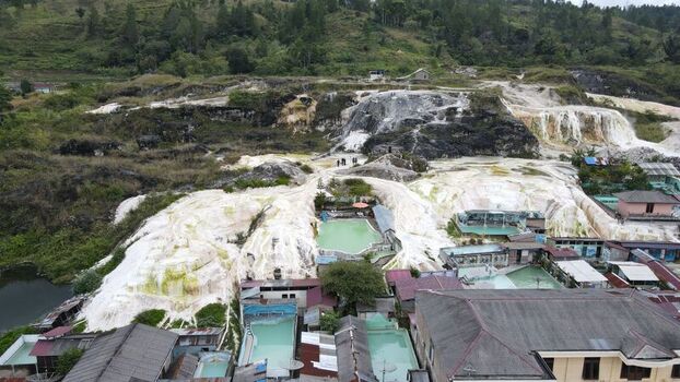 Aerial view of the Sipoholon Hot Springs featuring white limestone terraces turquoise thermal pools and surrounding lush hills in Tarutung North Sumatra Indonesia. Aerial view of the Sipoholon Hot Springs featuring white limestone terraces turquoise thermal pools and surrounding lush hills in Tarutung North Sumatra Indonesia.