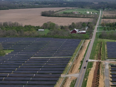 Lebanon United States 12 April 2026 Aerial view of a large solar farm with rows of photovoltaic panels next to a rural road and a red barn in the countryside.
