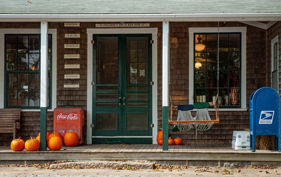 Edgartown United States 14 May 2026 View of Martha s Vineyard historic general store front with shingled walls green doors orange pumpkins and a vintage Coca Cola cooler.