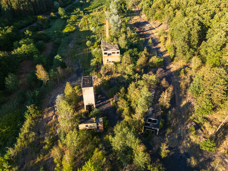 Aerial view of abandoned coal loading structures at the former mining settlement of Rakoczibanya Hungary surrounded by summer forest overgrown ground and access roads. Aerial view of abandoned coal loading structures at the former mining settlement of Rakoczibanya Hungary surrounded by summer forest overgrown ground and access roads.