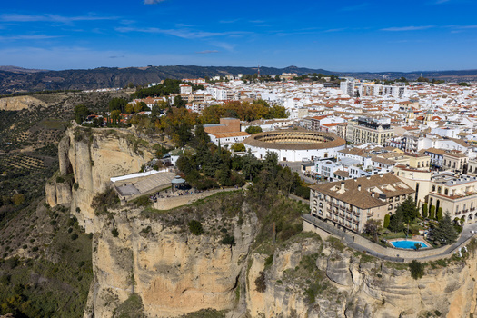 Aerial view of the historic Plaza de Toros bullring perched on the edge of a dramatic cliff overlooking the town of Ronda Andalusia Spain. Aerial view of the historic Plaza de Toros bullring perched on the edge of a dramatic cliff overlooking the town of Ronda Andalusia Spain.
