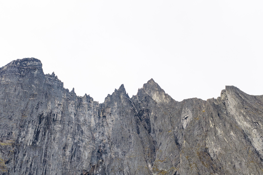 Aerial view of the steep jagged rock face of the Troll Wall featuring dramatic vertical cliffs and rugged mountain peaks in Andalsnes More og Romsdal Norway. Aerial view of the steep jagged rock face of the Troll Wall featuring dramatic vertical cliffs and rugged mountain peaks in Andalsnes More og Romsdal Norway.