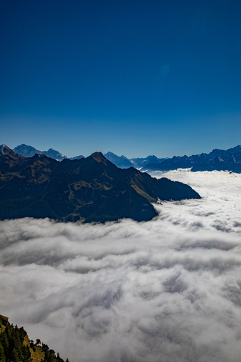 Aerial view of the Swiss Alps with mountain peaks rising above a thick sea of clouds under a clear blue sky in Airolo Ticino Switzerland. Aerial view of the Swiss Alps with mountain peaks rising above a thick sea of clouds under a clear blue sky in Airolo Ticino Switzerland.