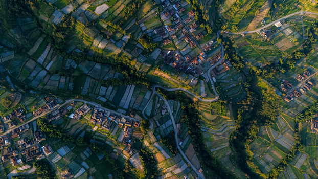 Aerial view of the village of Selo surrounded by terraced agricultural fields and winding roads in the lush landscape of Selo Central Java Indonesia. Aerial view of the village of Selo surrounded by terraced agricultural fields and winding roads in the lush landscape of Selo Central Java Indonesia.