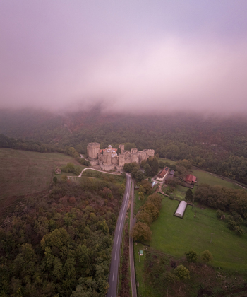 Aerial view of Manasija Monastery surrounded by lush forests and thick morning fog with a road leading to the historic fortress in Despotovac Pomoravski okrug Serbia.