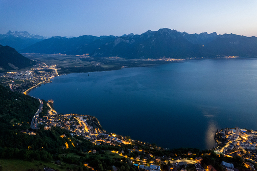 Aerial view of the illuminated Glion area along the shores of Lake Geneva at dusk with the Swiss Alps in the background Montreux Vaud Switzerland. Aerial view of the illuminated Glion area along the shores of Lake Geneva at dusk with the Swiss Alps in the background Montreux Vaud Switzerland.