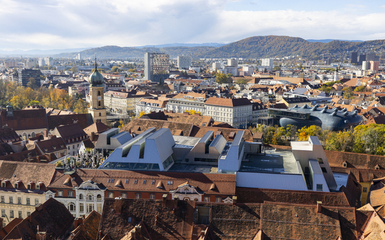 View of terracotta rooftops cascading towards modern architecture under a vast sky juxtaposing old world charm with contemporary design Graz Styria Austria. View of terracotta rooftops cascading towards modern architecture under a vast sky juxtaposing old world charm with contemporary design Graz Styria Austria.
