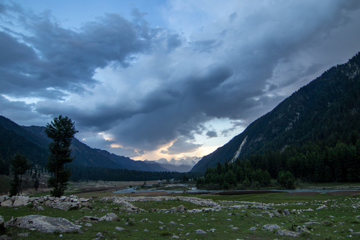 View of the dramatic landscape with storm clouds over mountain peaks green meadows and a river in Kumrat Valley Khyber Pakhtunkhwa Pakistan. View of the dramatic landscape with storm clouds over mountain peaks green meadows and a river in Kumrat Valley Khyber Pakhtunkhwa Pakistan.