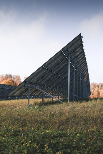 View of solar panels installed in a grassy field with autumn trees in the background under a clear sky in Otepaa Valga County Estonia. View of solar panels installed in a grassy field with autumn trees in the background under a clear sky in Otepaa Valga County Estonia.