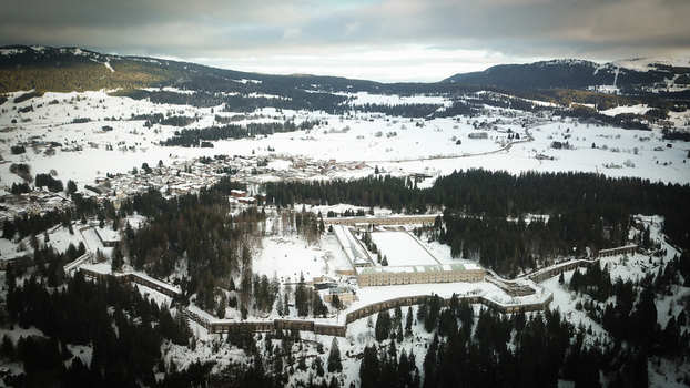 Aerial view of Le Fort des Rousses surrounded by snow covered pine forests and the village under a winter sky in Les Rousses Bourgogne Franche Comte France.